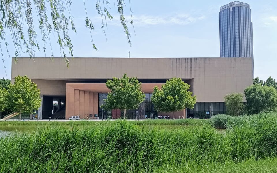 Tianjin Museum's broad stone facade rises behind a green wetland garden