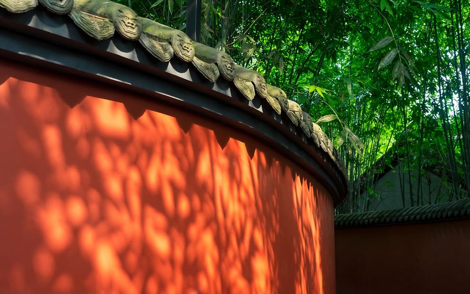 Curving red walls beneath dense bamboo shadows at Chengdu's Wuhou Shrine