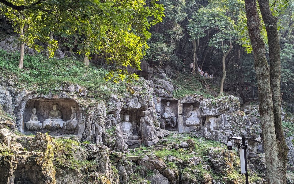 Historic Buddhist grotto carvings set into the wooded limestone cliffs of Feilai Peak at Lingyin