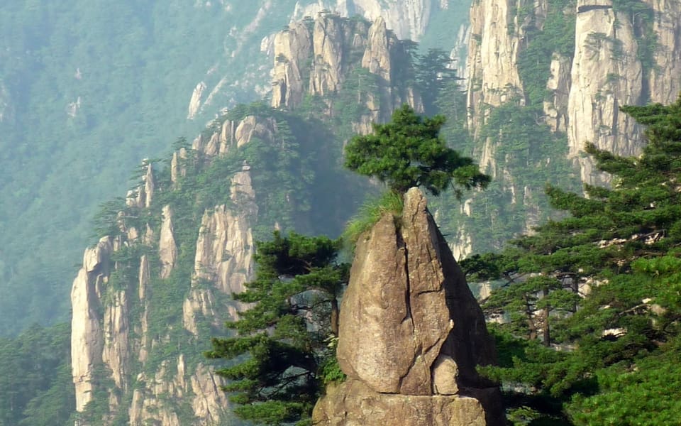 Granite pinnacles and forested slopes rising through haze in Mount Huangshan Scenic Area