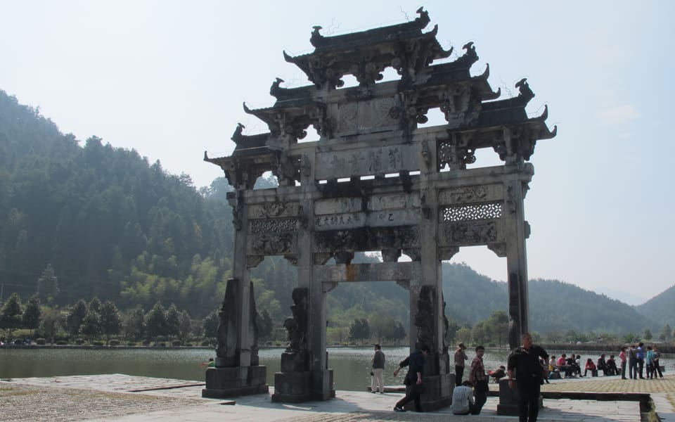 The carved stone Hu Wenguang memorial arch standing among village buildings in Xidi