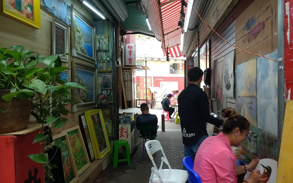 Artists painting canvases in a studio lane at Dafen Oil Painting Village in Shenzhen