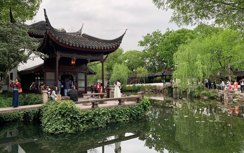 A dark timber pavilion reflected in a pond at Suzhou's Humble Administrator's Garden