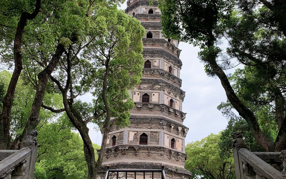 The leaning Yunyan Pagoda rising between mature trees at Suzhou's Tiger Hill