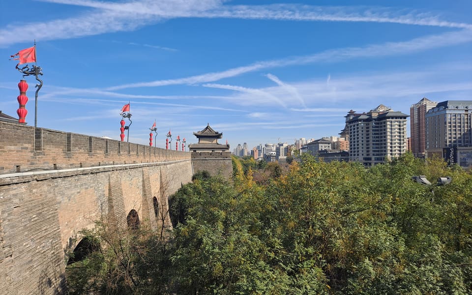 Xi'an City Wall and a watchtower extending beside trees and the modern city skyline