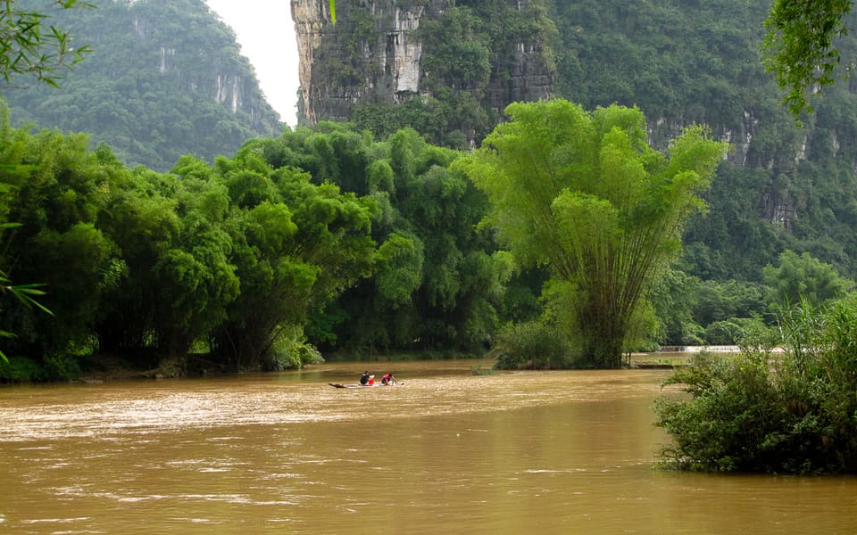 Small boat on the Yulong River framed by bamboo and limestone cliffs near Yangshuo