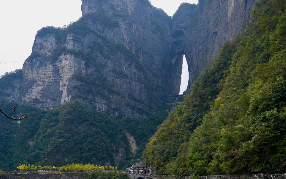 The natural Heaven's Gate arch opening high in Tianmen Mountain above forested cliffs