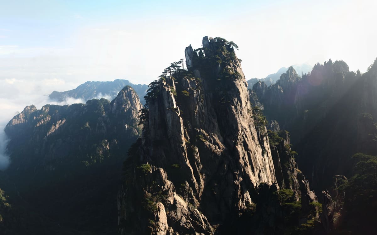 Granite peaks and forested ridges stretching across Mount Huangshan beneath layered clouds