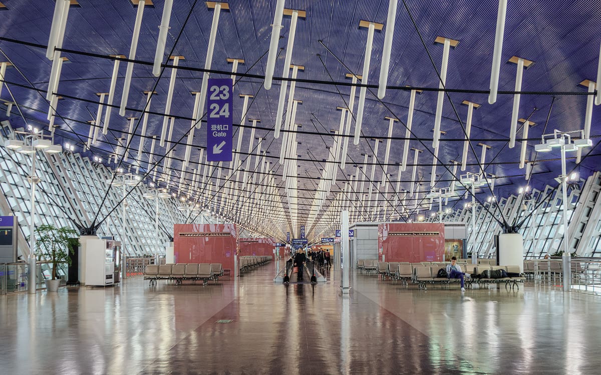 Blue-lit departure concourse at Shanghai Pudong International Airport with gate 23–24 signs