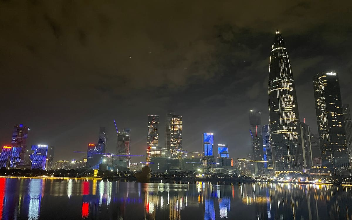 Illuminated Shenzhen Bay skyline and China Resources Headquarters reflected in the lake at Talent Park