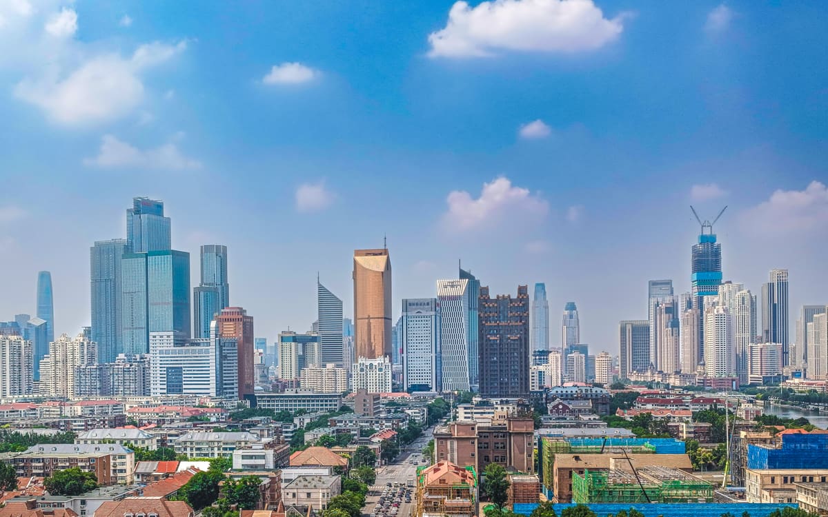 Central Tianjin skyline rising above older neighbourhoods under a vivid blue summer sky