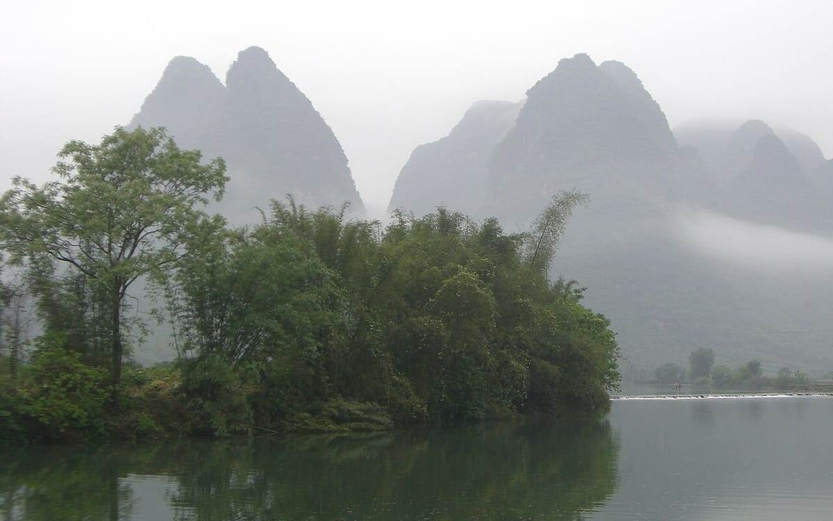 Misty limestone karst peaks reflected in the Yulong River near Yangshuo